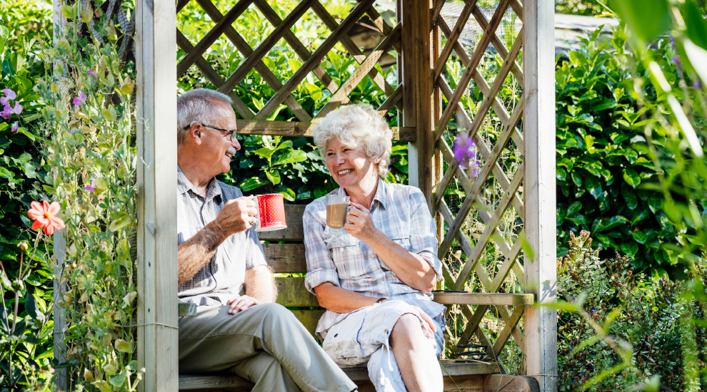 A senior couple sits and talks in a garden