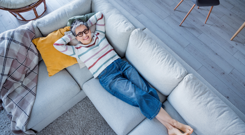 A woman lays on her couch enjoying her maintenance free home