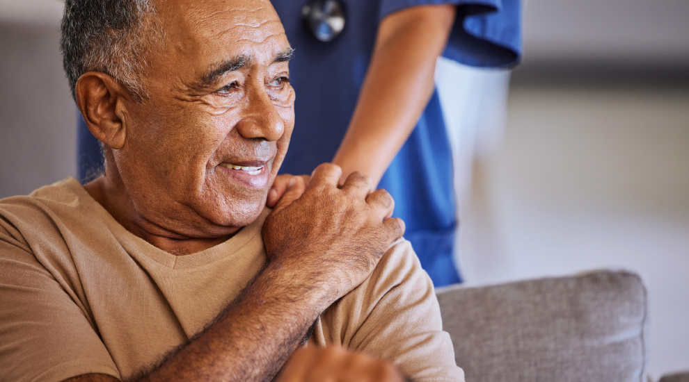 A senior man holds a nurses hand