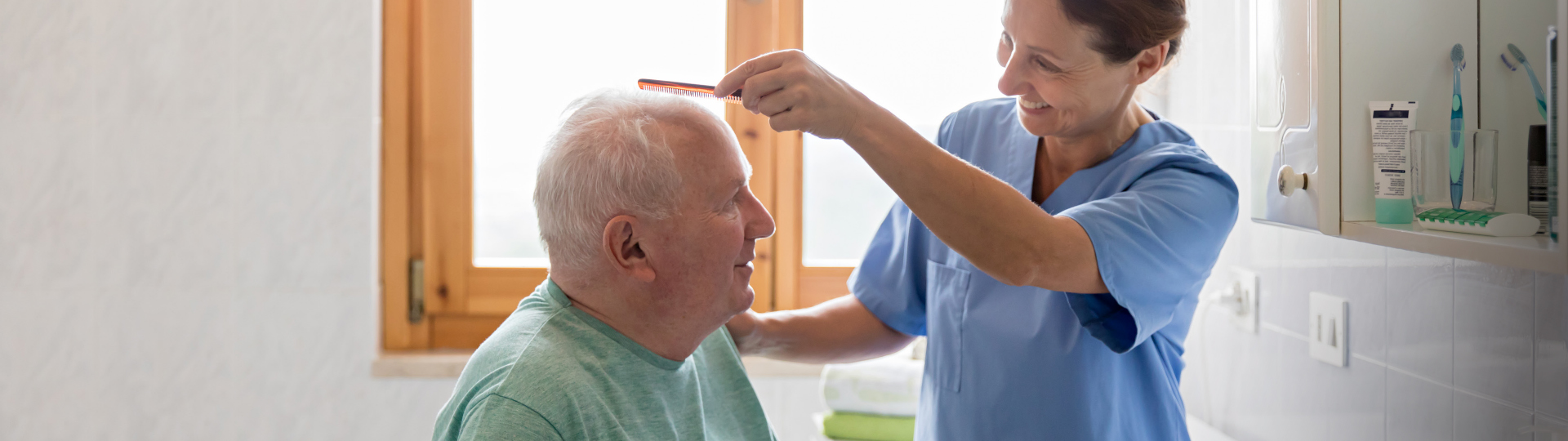 A senior man receives a haircut from a nurse