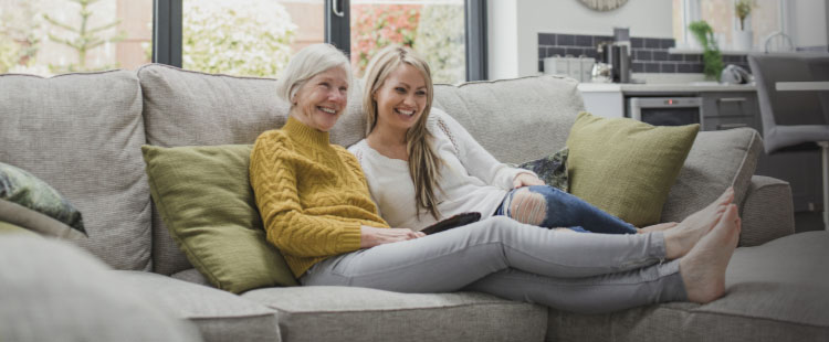 Two women relax on a couch at a senior living community