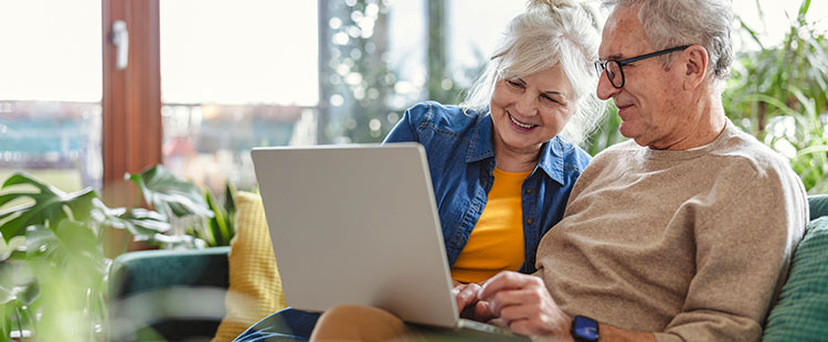 A senior man and woman smile as they look at a computer in Quitman GA